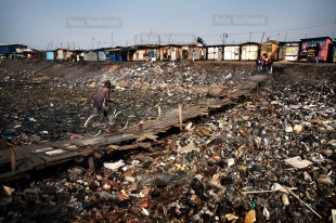 A man crosses a severely polluted river in the suburb of Agbogbloshie, in Accra, Ghana. When the rains come much of this waste will be washed to the sea.